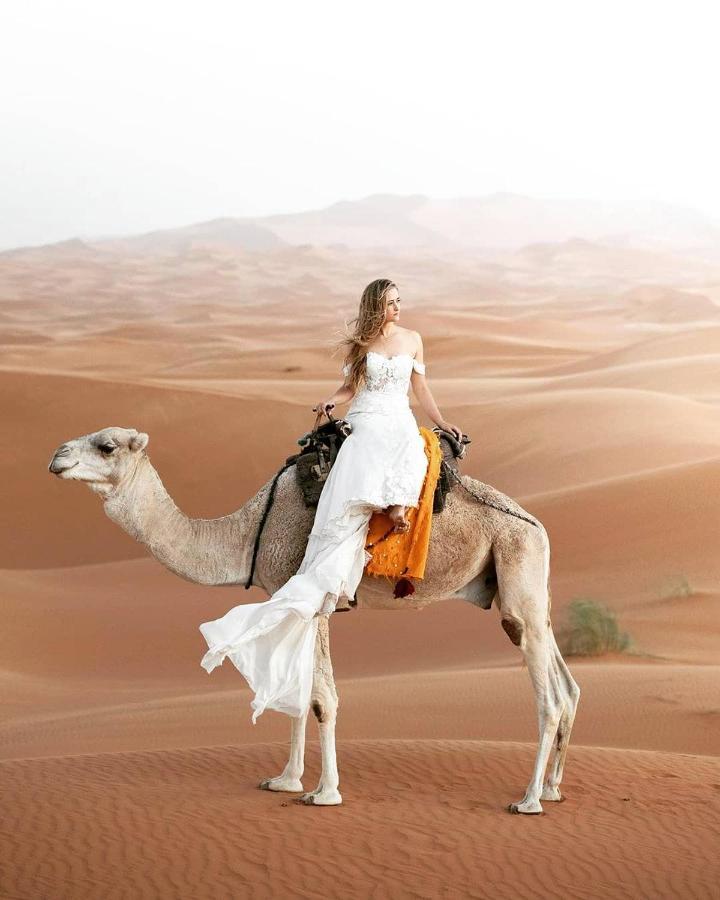 Hotel Sahara Majestic Luxury Camp Merzouga Esterno foto A woman riding a camel in the desert
